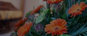A close up of some orange funeral floral arrangements, available as part of the Selsdon & District funeral floristry services tinted black.