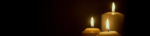 A close up of three lit candles on a black background.